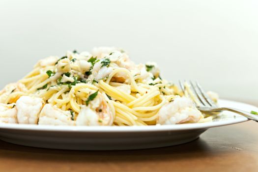 A delicious shrimp scampi pasta dish with calamari parsley garlic and olive oil. Shallow depth of field.