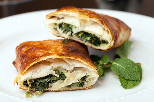 Greek spanakopita or spinach pie on a white plate.  Shallow depth of field.