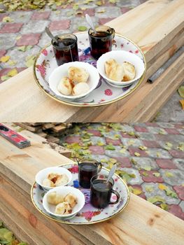 Two cups of black tea with donuts in the bowls on a tray