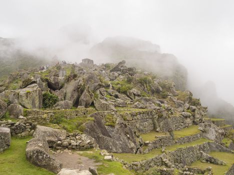 Scattered stones in the ruins site of a pre-Columbian 15th-century Inca site of Machu Picchu after rain in Machupicchu District, Urubamba Province, Cusco Region, Peru.