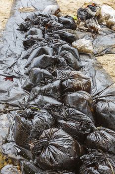 Row of Plastic bags which contain crude oil from the clean up operation on oil spill accident on Ao Prao Beach at Samet island on July 2013 in Rayong, Thailand.