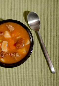 beef soup with vegetables on green with spoon