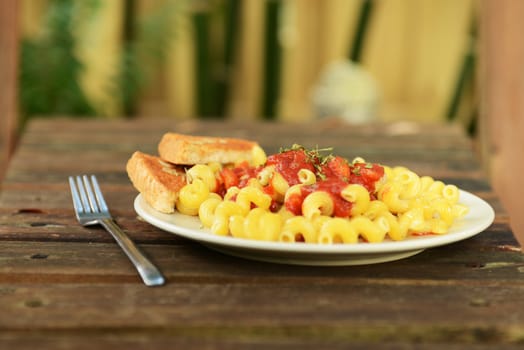 pasta with garlic bread on wood table outdoors