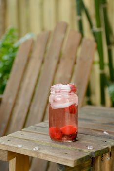 summer drink in mason jar outside with strawberries