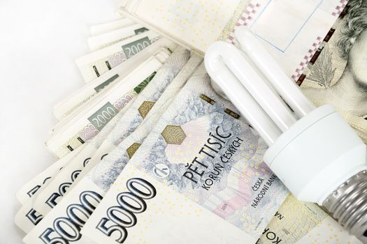 saving money with energy saving bulb concept with czech banknotes crown