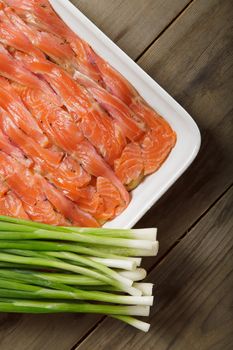 The dish for baking with thin slices of salmon and spring onions