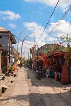 BALI, INDONESIA - SEP 19: Tourist street decorated by traditional penjor with shops and tours on Sep 19, 2012 in Ubud, Bali, Indonesia. Ubud is popular tourist attraction. 