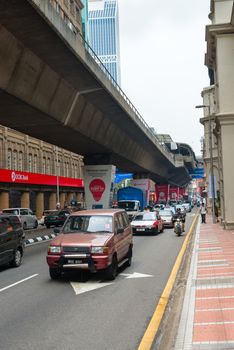 KUALA LUMPUR - JUN 15: City street with cars and  monorail way under road on Jun 15, 2013 in Kuala Lumpur, Malaysia. Kuala Lumpur is served by three separate rail systems with underground, elevated or at-grade lines.