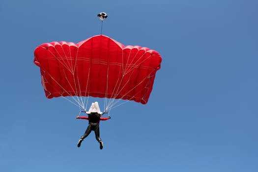 parachutist with red parachute on blue sky