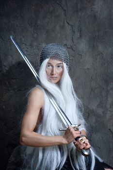 Androgyny girl in armor with a sword and looking at the camera