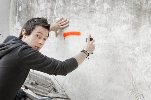 Graffiti artist about to start spraying a wall, looking at camera