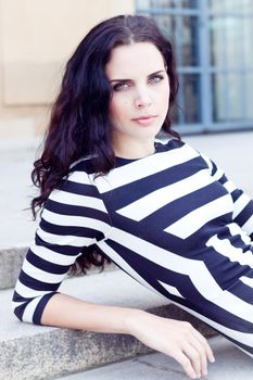 attractive woman in sexy dress in stripes sitting on stairs