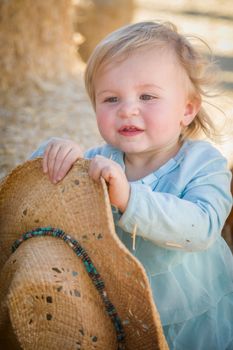 Adorable Baby Girl with Cowboy Hat in a Country Rustic Setting at the Pumpkin Patch.