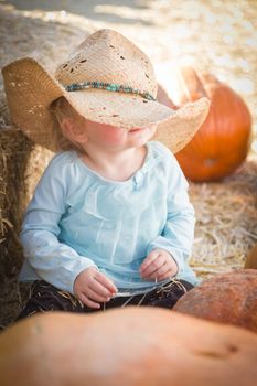 Adorable Baby Girl with Cowboy Hat in a Country Rustic Setting at the Pumpkin Patch.