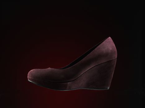red suede shoes over dark red background