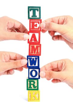 Closeup of many hands holding up letters to spell the work teamwork 