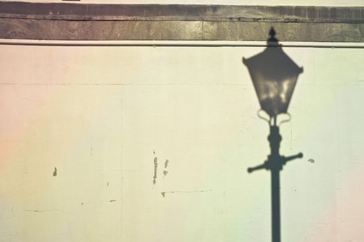 Lamp post shadow cast on a stone wall