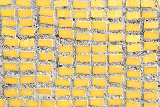 small yellow tiles on a stone surface as a background