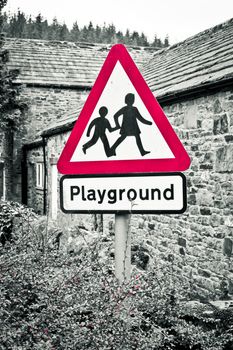 A playground warning sign with selective color desaturation