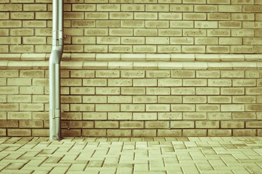 A metal drainpipe against a modern brick wall as a background