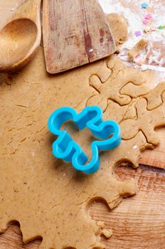 Preparation Gingerbread Cookies with Dough, Flour, Kitchen Utensils and Gingerbread Men Shape closeup on Wooden background
