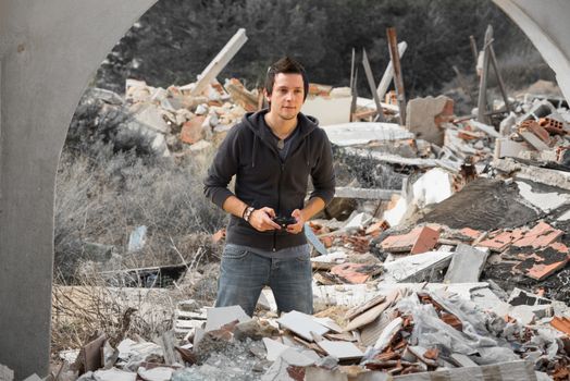 A young guy gaming amidst piles of rubble, a modern life concept