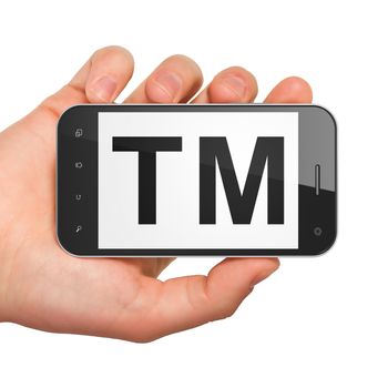 Law concept: hand holding smartphone with Trademark on display. Generic mobile smart phone in hand on White background.