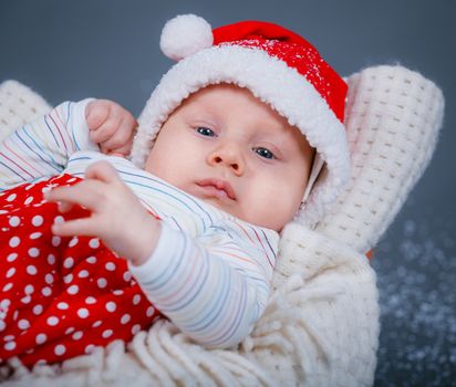 Christmas theme. A baby boy in a Santa suit in studio