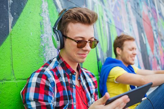 Portrait of happy teens boy near painted wall listening to music