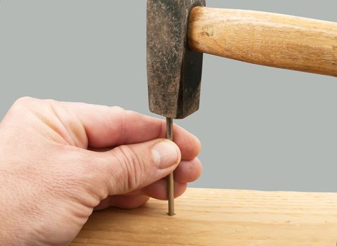 hands with hammer hitting a nail