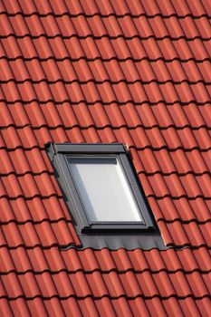 Red tiles of the house's roof with a window in center