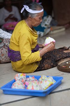 TAMPAK SIRING, BALI, INDONESIA - SEP 21: Woman makes sweets for balinese traditional offerings to gods in temple Puru Tirtha Empul on Sep 21, 2012 in Tampak Siring, Bali, Indonesia