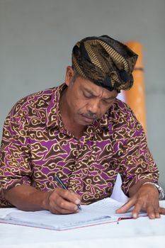 TAMPAK SIRING, BALI, INDONESIA - SEP 21: Balinese man maintain records in register book in temple Puru Tirtha Empul on Sep 21, 2012 in Tampak Siring, Bali, Indonesia