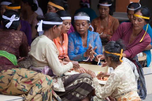 TAMPAK SIRING, BALI, INDONESIA - SEP 21: Women make sweets for balinese traditional offerings to gods in temple Puru Tirtha Empul on Sep 21, 2012 in Tampak Siring, Bali, Indonesia