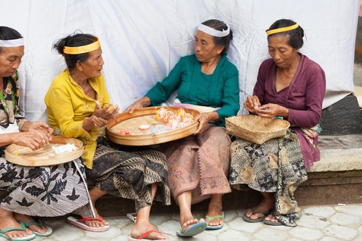 TAMPAK SIRING, BALI, INDONESIA - SEP 21: Women make sweets for balinese traditional offerings to gods in temple Puru Tirtha Empul on Sep 21, 2012 in Tampak Siring, Bali, Indonesia