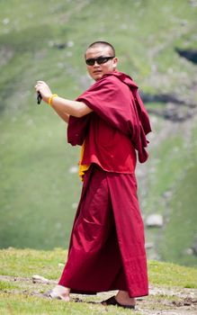 Himachal Pradesh, India - August 16, 2011: Buddhist monk in glasses is taking photos, mountains on background