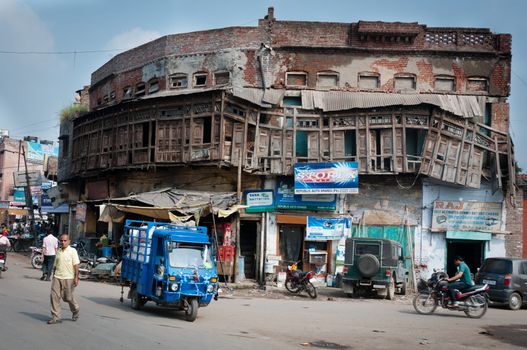 Amritsar, India - August 26, 2011: Old damaged building with shops and car services on first floor, located near Amritsar railway station, people and transport are in front of the building