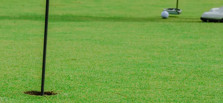 Golf ball on a green, in front of the hole,