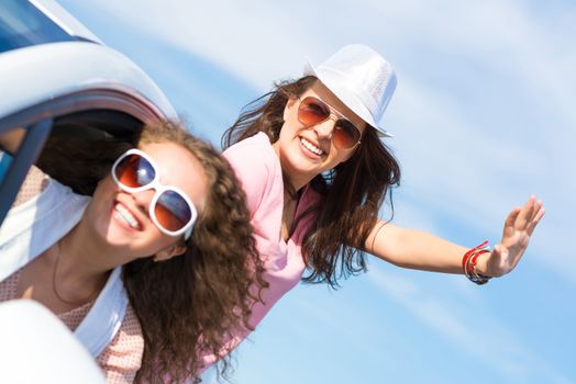 young woman got out of the car window, holds the hand hat, waving his hand and laughing