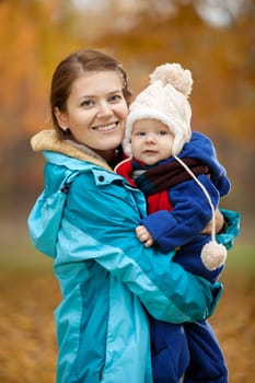 Portrait of young woman and her baby son in autumn park