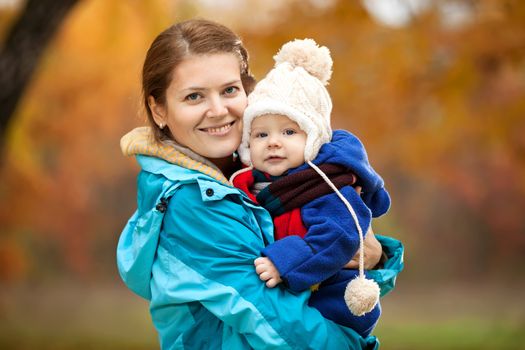 Portrait of young woman and her baby son in autumn park