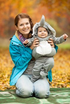 Portrait of young woman and her baby boy dressed in elephant costume in autumn park