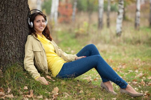 Young girl listening to music on headphones while sitting on grass