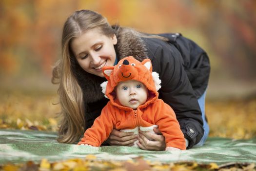 Young woman with baby dressed in fox costume having fun in autumn park