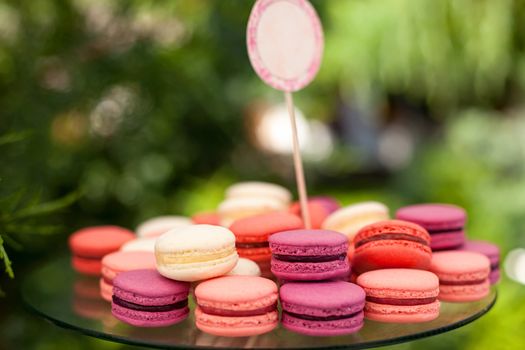 Tasty colorful macaroons on plate outdoors, shallow depth of field