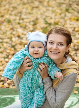 Portrait of young woman and her baby son in autumn park