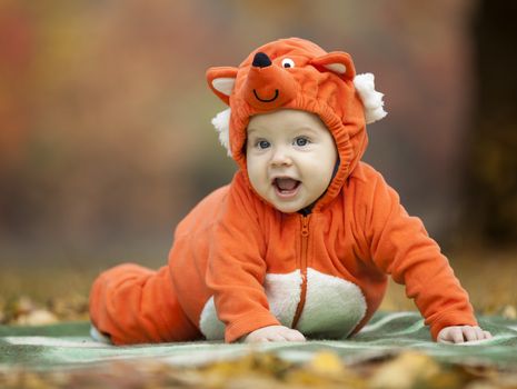 Baby boy dressed in fox costume in autumn park