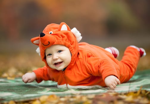 Baby boy dressed in fox costume in autumn park