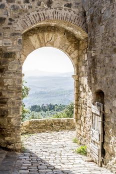 Archway in San Quirico with view to the Tuscan landscape in Tuscany, Italy