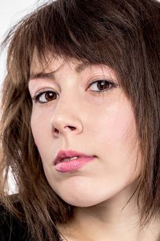 Closeup portrait of the face of an attractive young brunette woman looking at the camera with slightly parted lips